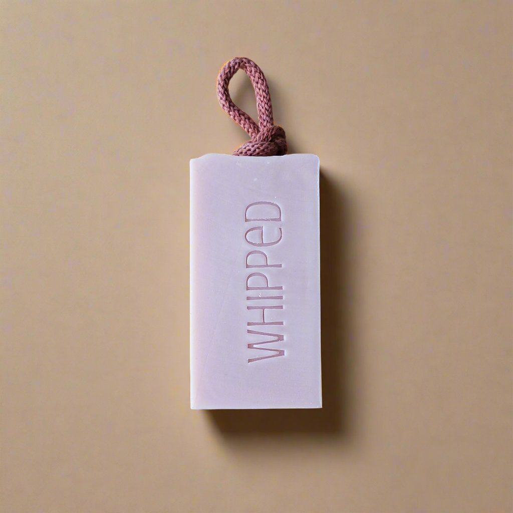 Bar of soap with 'WHIPPED' text on a beige background