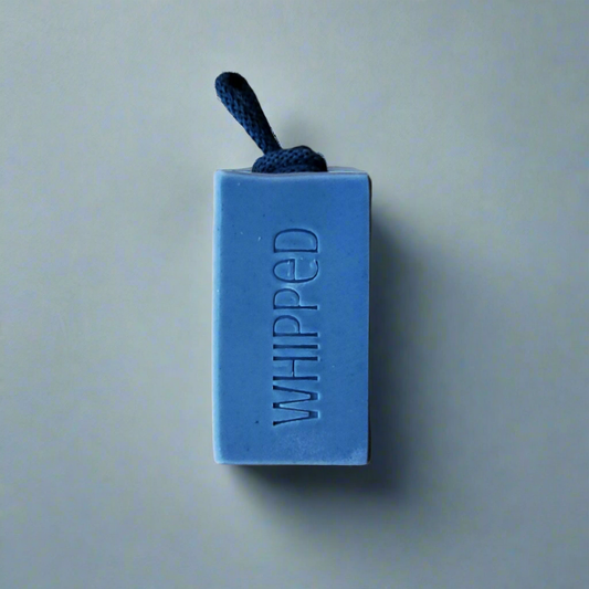 Blue bar of soap with 'WHIPPED' text on a light green background